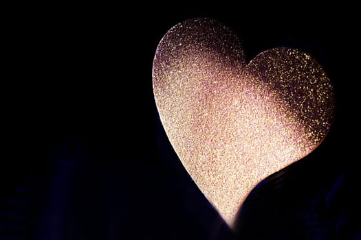Golden shiny heart on black background