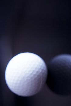 White golf ball somewhat out of focus on dark background. No people