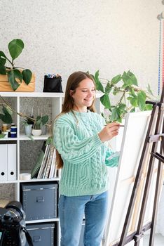 Young woman artist in mint green sweater holding color palette working at home