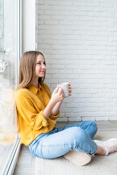 Young attractive woman drinking tea sitting on the floor