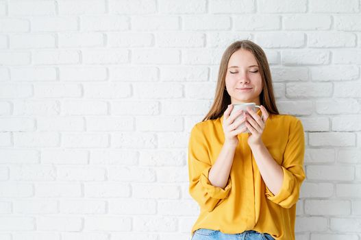 Attractive teenager woman in yellow shirt drinking tea