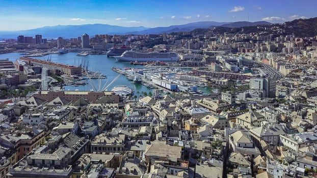 Aerial panoramic drone view of buildings and streets surrounding Port of Genoa.Cruise ships and ferries in port.Old famous city of Italy, with beautiful architecture, houses, roofs, buildings.