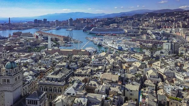 Aerial panoramic drone view of buildings and streets surrounding Port of Genoa.Cruise ships and ferries in port.Old famous city of Italy, with beautiful architecture, houses, roofs, buildings.