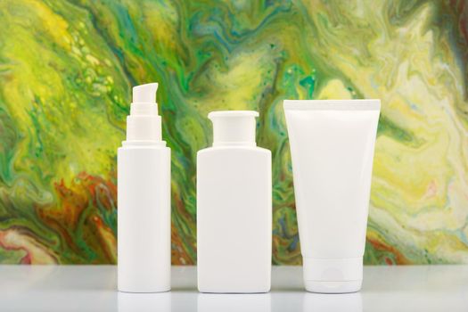 White cosmetic bottles on white table against bright green abstract background. Concept of skin care products, skin care and beauty