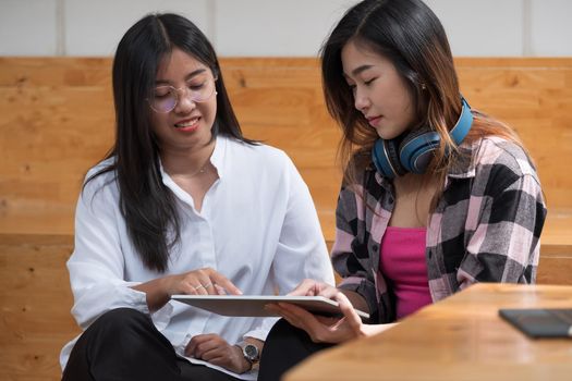 Happy young asian student girls studying at home with digital tablet computers