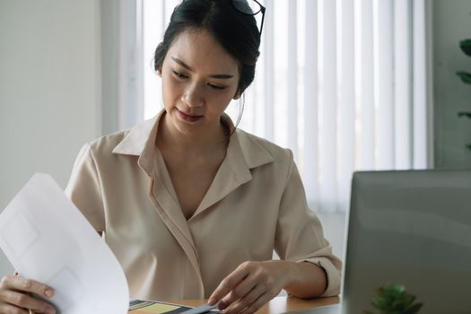 Female asian businesswoman analyzing the business report with laptop computer in the office