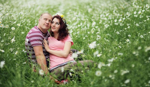 Couple in love guy and girl in a field of white daisies and green grass. 