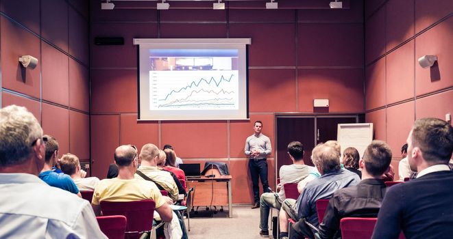 Speaker giving a talk in conference hall at business event. Unrecognizable people in audience at conference hall. Business and Entrepreneurship concept.