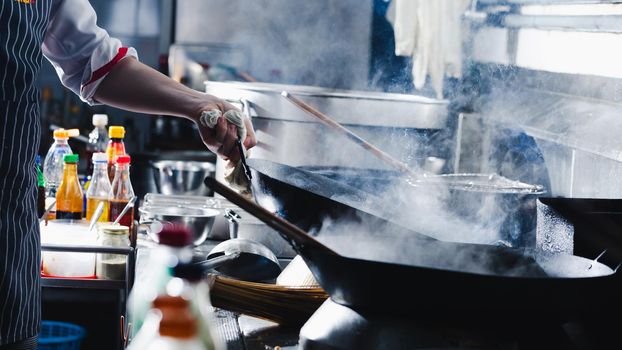 Chef stir fry in wok. Dramatic cooking with fire hard in kitchen