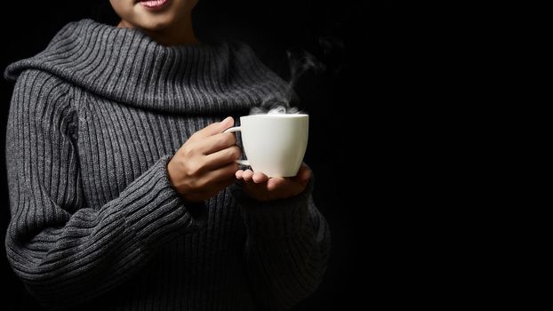 Cup of coffee in the women's hand on dark background