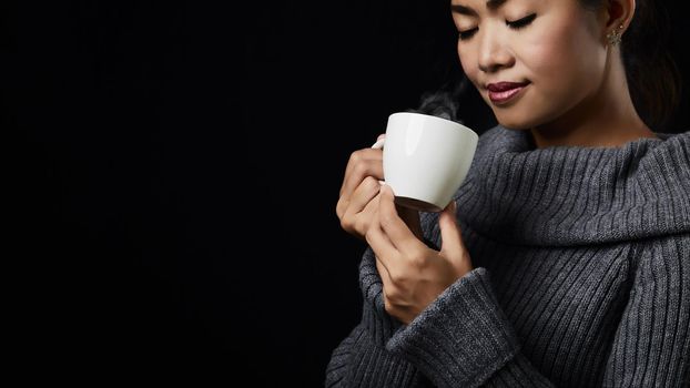 Cup of coffee in the women's hand on dark background