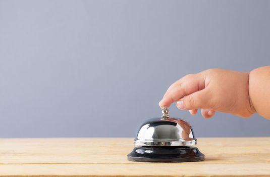 Hand s' child to press the bell service on wood table. Bell of service concept