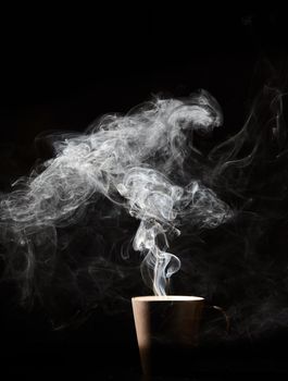 Steaming coffee cup on dark background, White smoke on dark