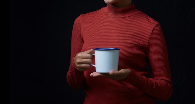 Cup of coffee in the women's hand on dark background