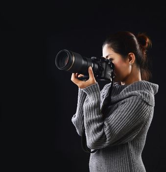 Female photographer using DSLR camera working on studio lighting