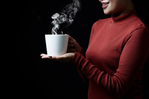 Cup of coffee in the women's hand on dark background