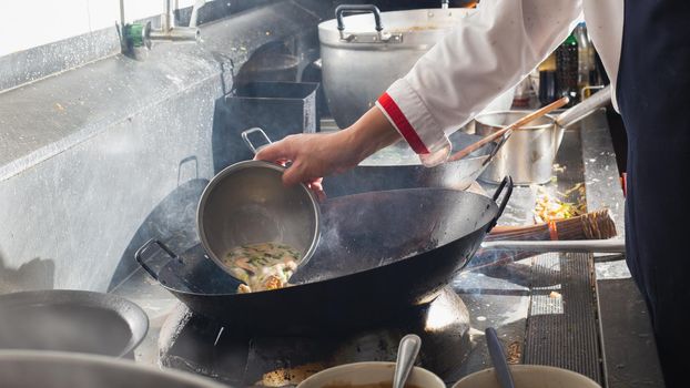 Chef stir fry in wok. Professional cooking in kitchen