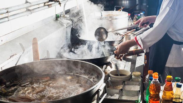 Chef stir fry in wok. Professional cooking in kitchen