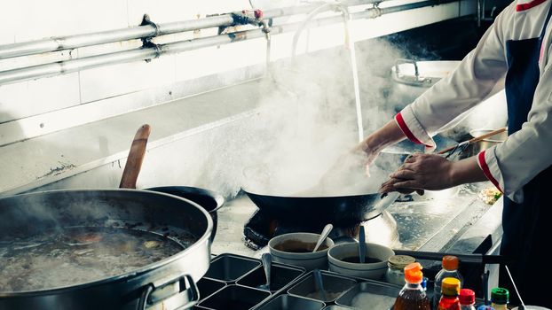 Chef stir fry in wok. Professional cooking in kitchen