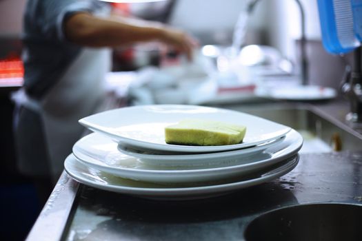 Man washing dish on sink at restaurant