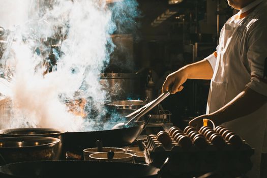 Chef stir fry in wok. Dramatic cooking with fire hard