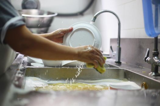 Woman washing dish on sink at restaurant