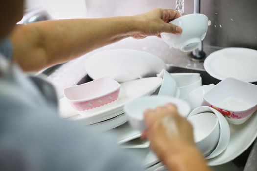 Woman washing dish on sink at restaurant