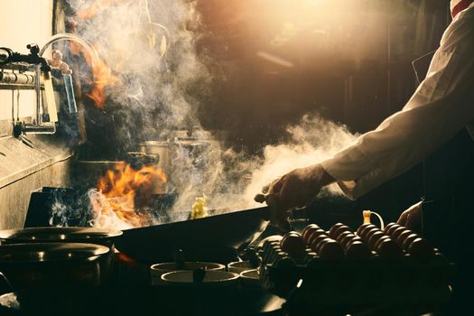 Chef stir fry in wok. Dramatic cooking with fire hard