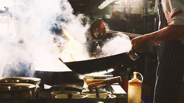 Chef stir fry in wok. Dramatic cooking with fire hard
