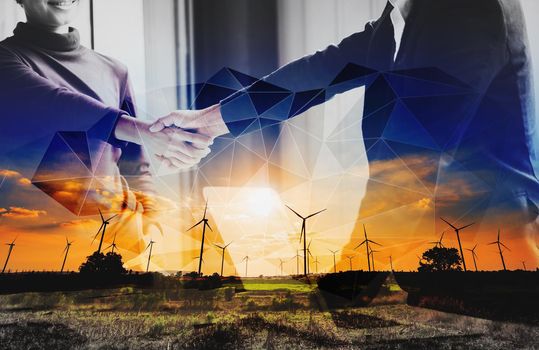 Double exposure of two business persons shaking hands and turbine energy wind