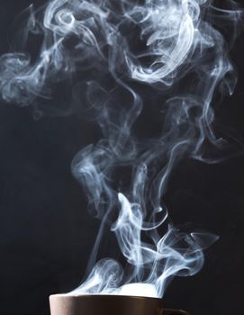 Steaming coffee cup on dark background, White smoke on dark