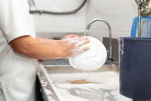 Man washing dish on sink at restaurant