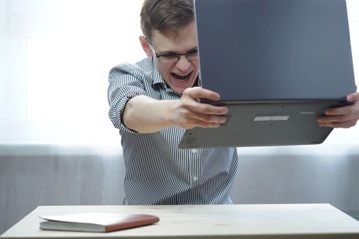 A young man of European appearance gets angry after remote work or education at the computer. High quality photo