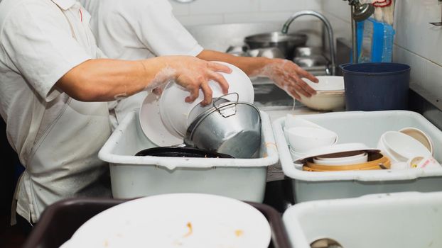 Man washing dish on sink at restaurant