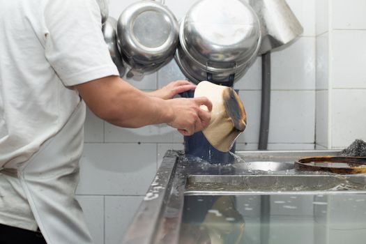 Man washing dish on sink at restaurant