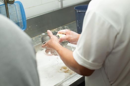 Man washing dish on sink at restaurant