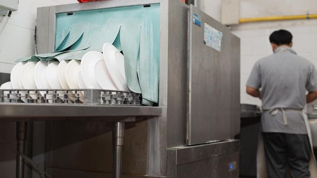 Man washing dish on sink at restaurant