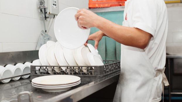 Man washing dish on sink at restaurant