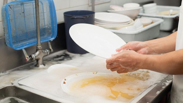 Man washing dish on sink at restaurant