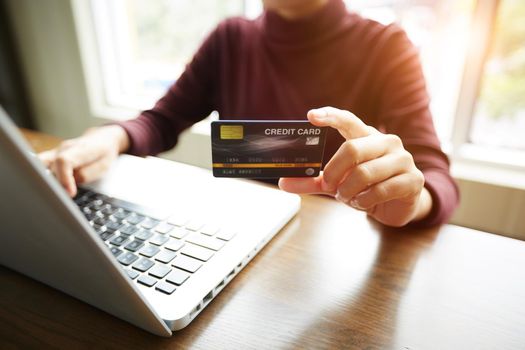 Hands holding plastic credit card and using notebook. Online shopping lifestyle concept