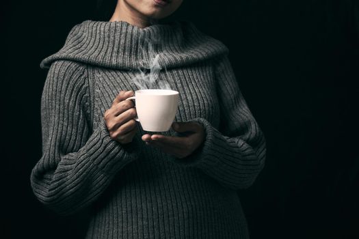 Cup of coffee in the women's hand on dark background