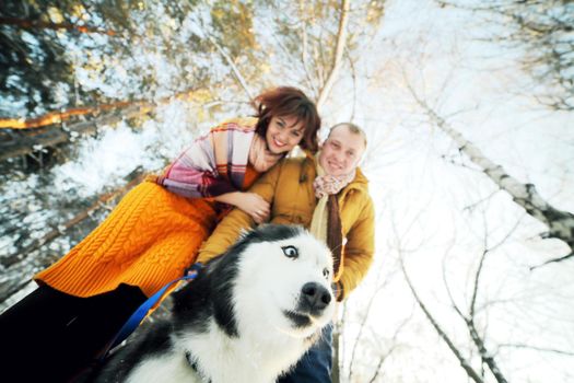 Guy and girl with husky dog in winter in the forest, bottom view. 