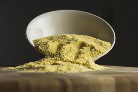 Corn starch in the white bowl on the desk, black background. High quality photo