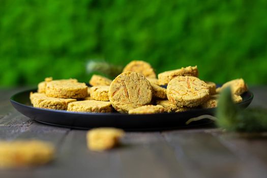 Carrots biscuits, wooden table, moss in the background. High quality photo