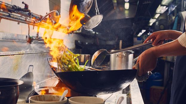 Chef stir fry cooking in kitchen