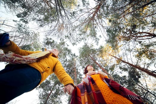 Cheerful young couple walking in the winter forest, low angle.