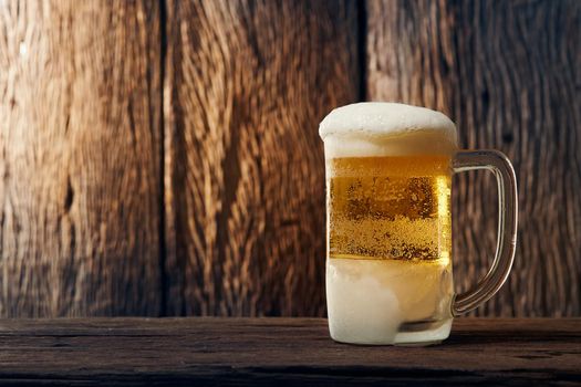 Beer in mug on wooden table with wooden background