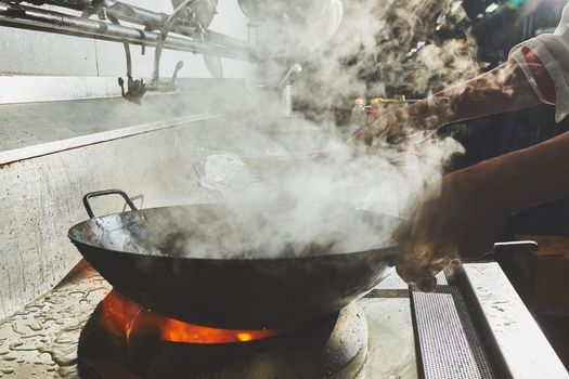 Chef stir fry cooking in kitchen