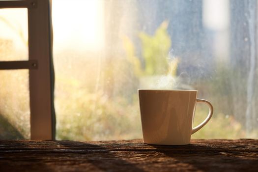 A cup of coffee on the wood floor in the morning sunshine beside window