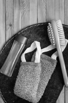 Accessories for visiting a bath or sauna on a wooden background: a washcloth, a mat, a massage brush and shower gel. Top view with copy space. Flat lay